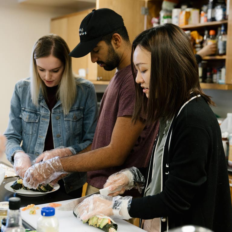 Three students prepare sushi in cooking class