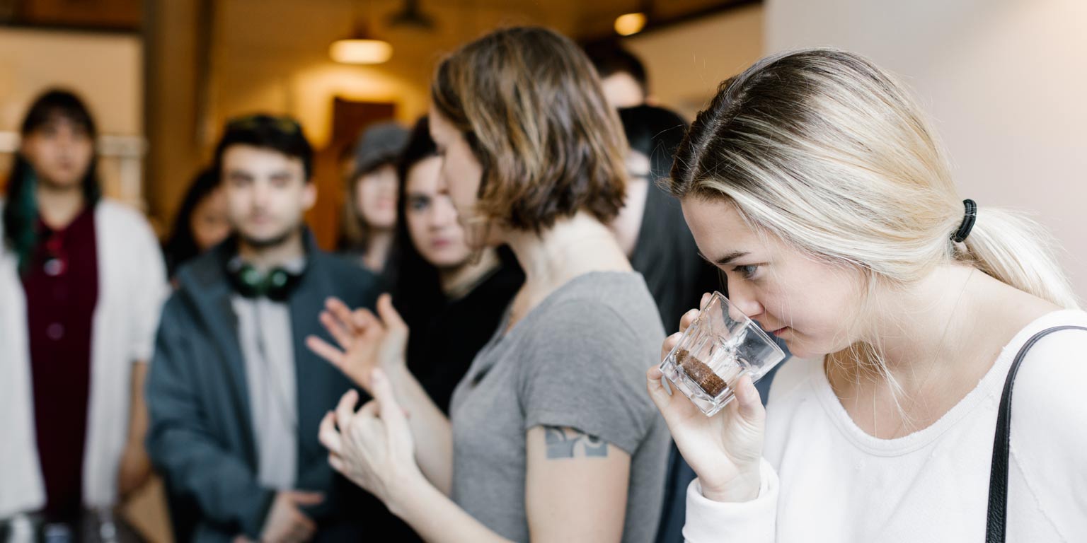 Student sniffs coffee grounds during a tasting event