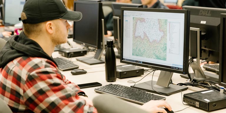 Student works with GIS software on a desktop computer